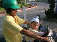 Man and a small child with no helmet riding a motorbike